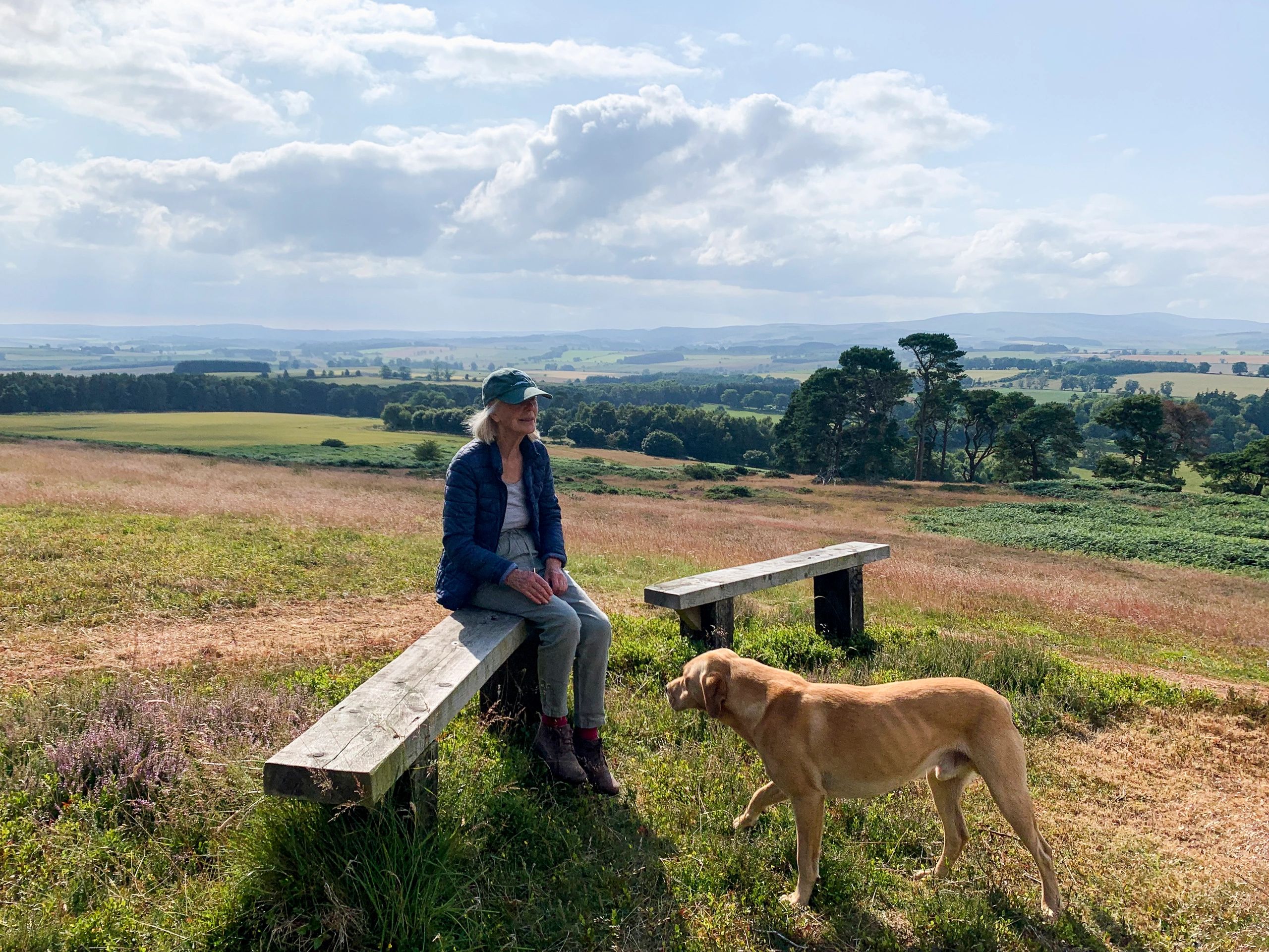 Woman sitting outdoors with her dog in the countryside