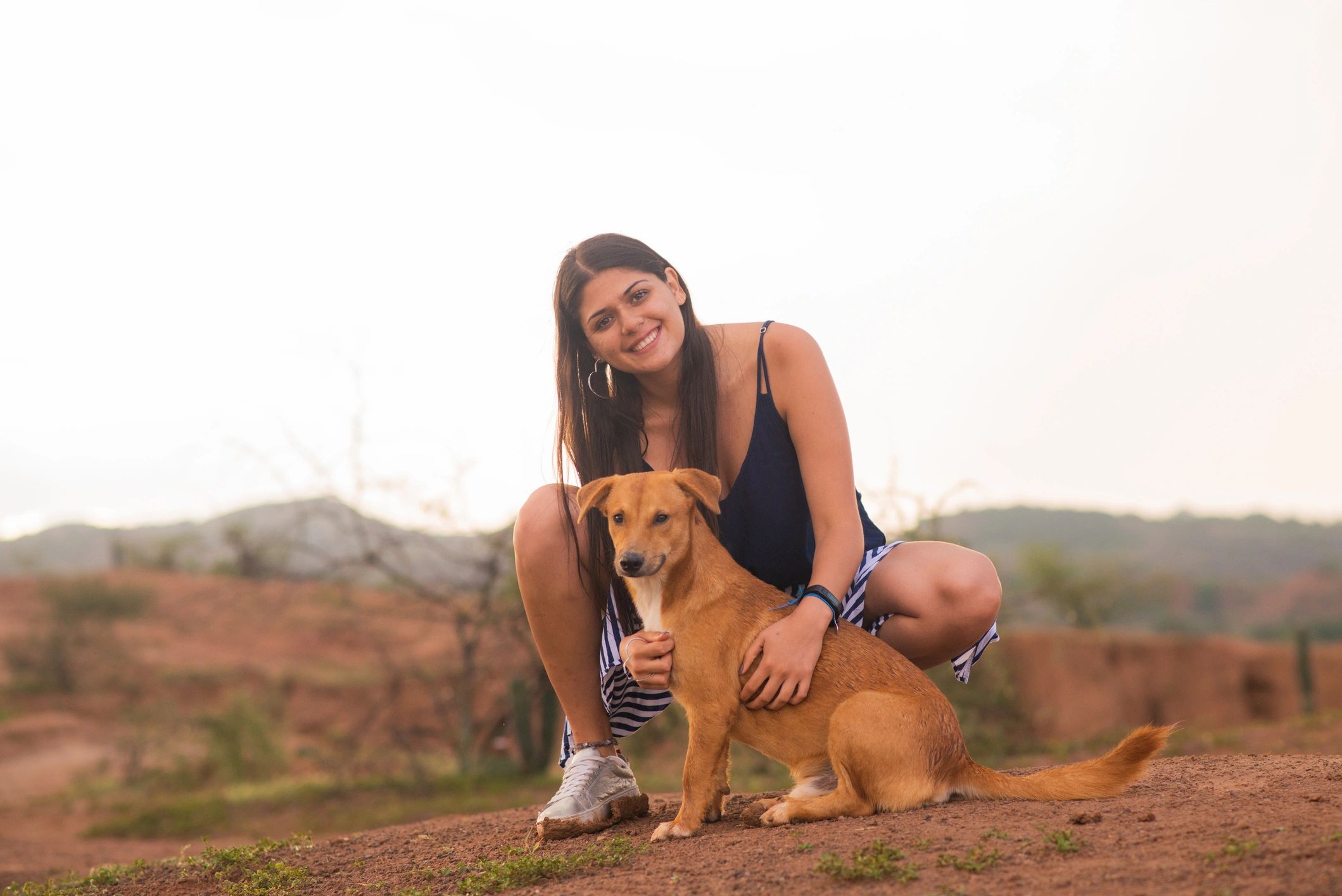 Woman outdoors petting her dog in a countryside setting